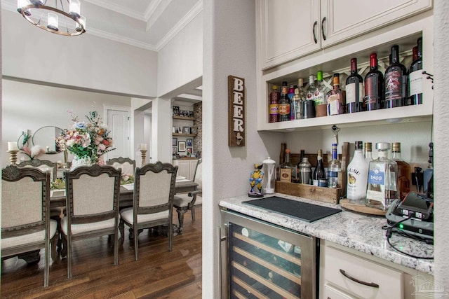 indoor dry bar featuring crown molding, beverage cooler, dark wood-type flooring, and a chandelier