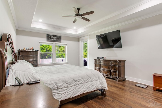bedroom with a tray ceiling, wood finished floors, ornamental molding, baseboards, and a ceiling fan