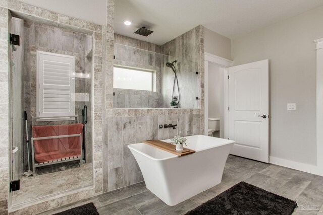 bathroom with tile walls, a stall shower, a soaking tub, and toilet