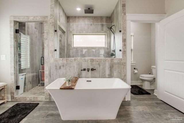 bathroom featuring a stall shower, toilet, a soaking tub, and tile walls