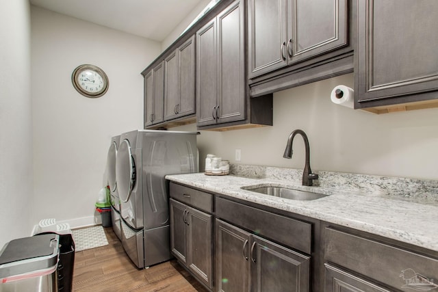 washroom featuring cabinet space, washing machine and dryer, wood finished floors, and baseboards