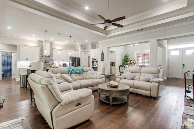 living room with a ceiling fan, dark wood finished floors, crown molding, a tray ceiling, and recessed lighting