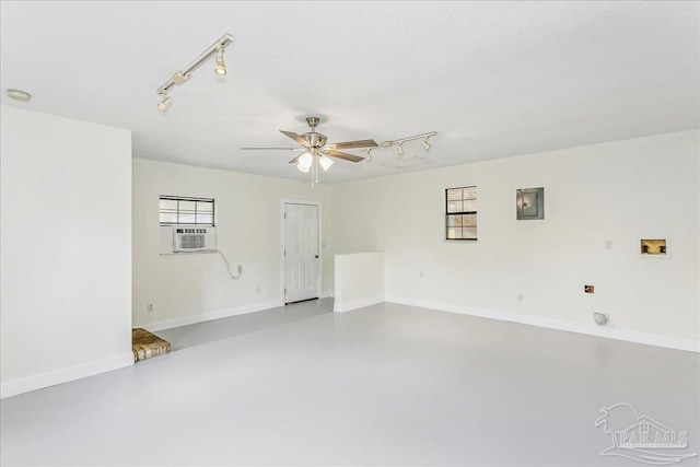 spare room with a ceiling fan, plenty of natural light, electric panel, rail lighting, and concrete floors