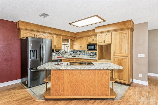 kitchen with stainless steel refrigerator with ice dispenser, light wood-style floors, visible vents, and stovetop