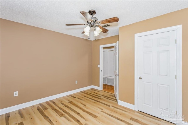 unfurnished bedroom with ceiling fan, a textured ceiling, visible vents, baseboards, and light wood-style flooring