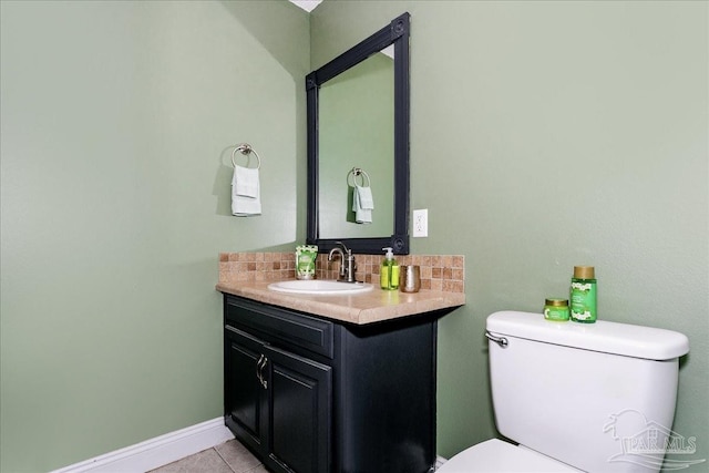half bathroom featuring vanity, tile patterned flooring, toilet, baseboards, and backsplash