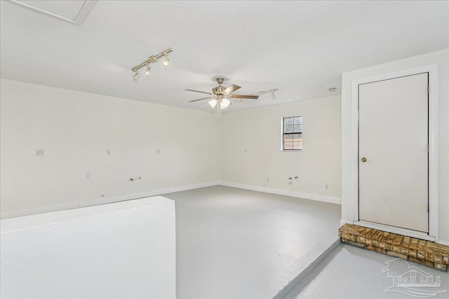 spare room with rail lighting, baseboards, a ceiling fan, and concrete floors