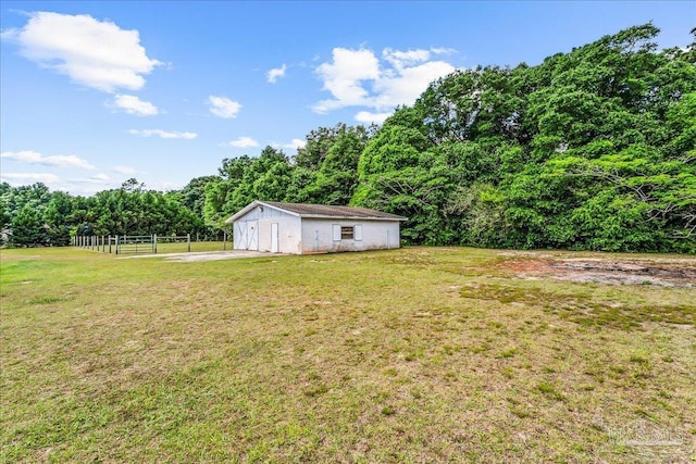 view of yard with fence, a view of trees, and an outdoor structure