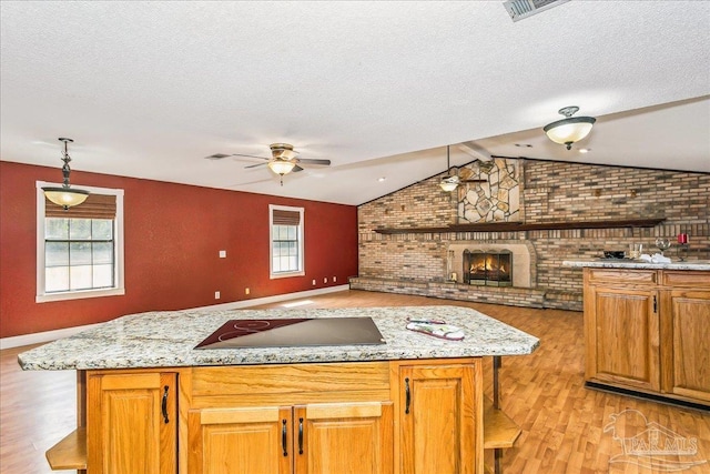 kitchen with vaulted ceiling, light wood-type flooring, brick wall, and black electric cooktop
