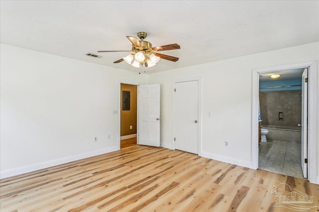 unfurnished bedroom featuring baseboards, visible vents, ensuite bathroom, and light wood finished floors