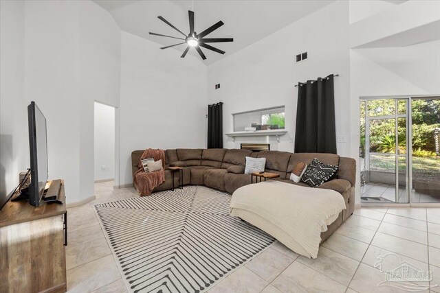 tiled living room with ceiling fan and high vaulted ceiling