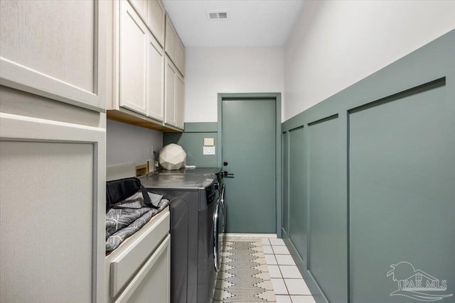 washroom featuring cabinets, washing machine and dryer, and light tile patterned floors