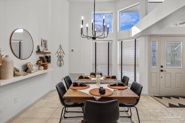 dining room with light tile patterned flooring, an inviting chandelier, and a high ceiling