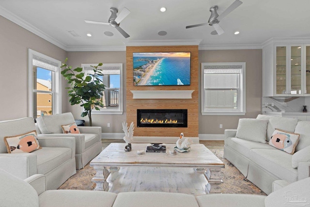 living area with a fireplace, ceiling fan, light wood-style flooring, and crown molding