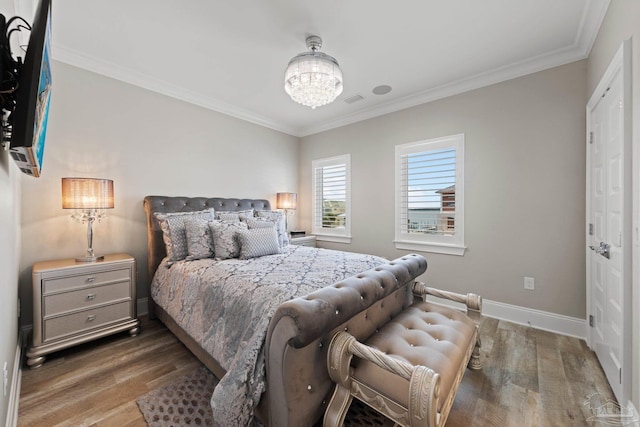 bedroom featuring baseboards, ornamental molding, wood finished floors, and an inviting chandelier