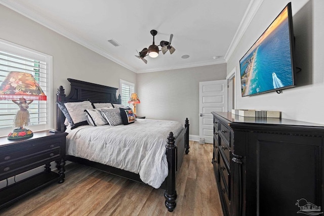 bedroom with visible vents, ornamental molding, light wood-type flooring, and a ceiling fan