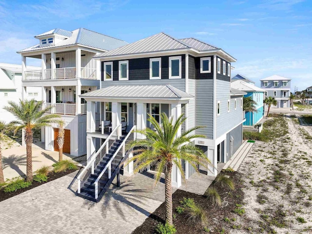 beach home featuring stairway, metal roof, covered porch, and driveway