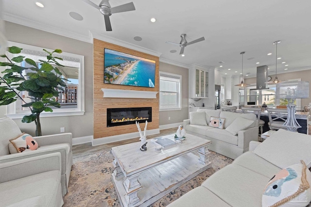 living area featuring crown molding, light wood-type flooring, recessed lighting, ceiling fan, and a fireplace