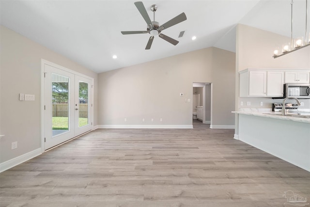 unfurnished living room with sink, high vaulted ceiling, ceiling fan with notable chandelier, and light wood-type flooring