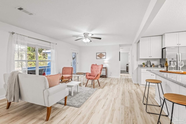 living room featuring ceiling fan and light hardwood / wood-style flooring