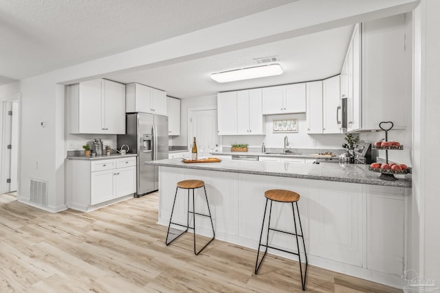 kitchen with kitchen peninsula, stainless steel appliances, and white cabinetry