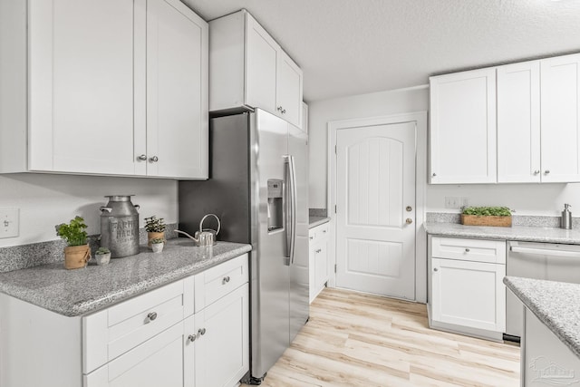 kitchen featuring white cabinets, light stone counters, light wood-type flooring, and appliances with stainless steel finishes