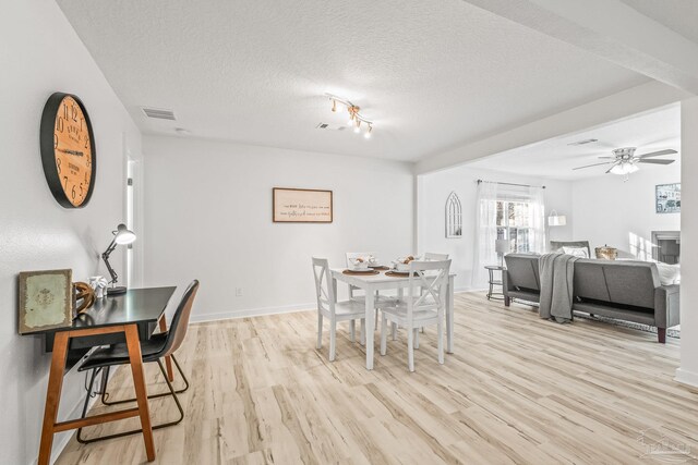 dining space with a textured ceiling, light hardwood / wood-style floors, and ceiling fan