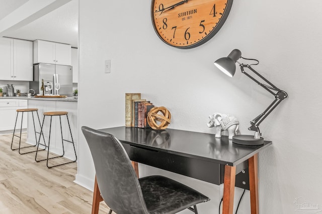 bar featuring light hardwood / wood-style floors, stainless steel fridge, and white cabinetry