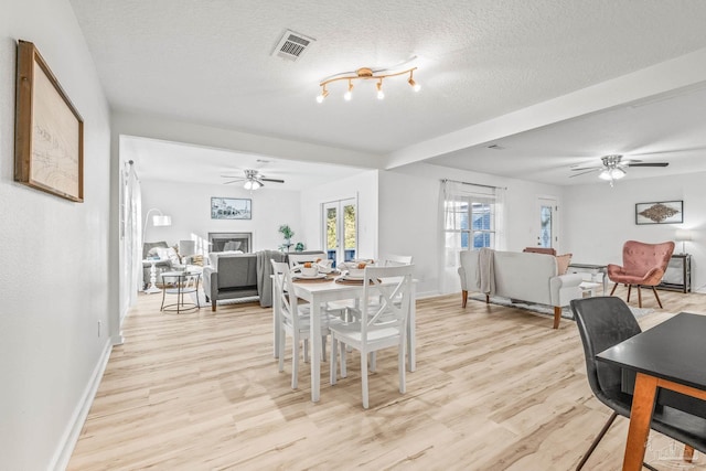 dining area featuring ceiling fan, light hardwood / wood-style floors, and a textured ceiling