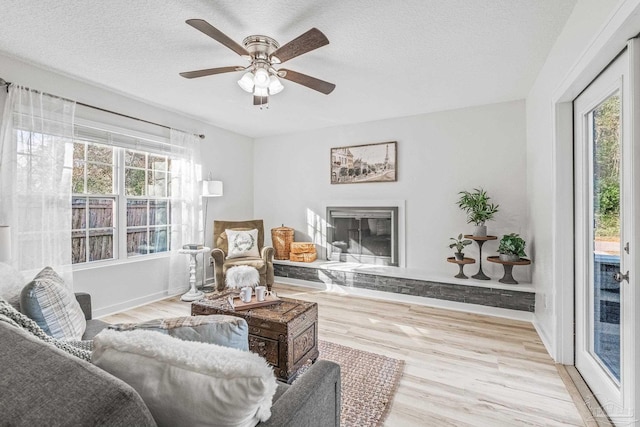 living room featuring a textured ceiling, light wood-type flooring, and ceiling fan