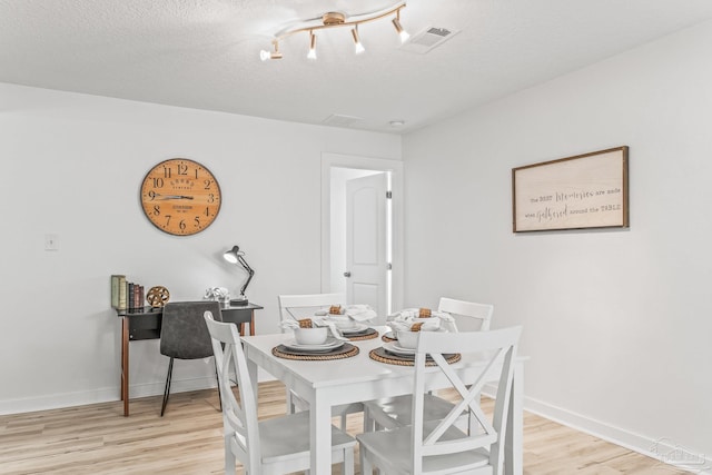 dining space with light hardwood / wood-style flooring and a textured ceiling