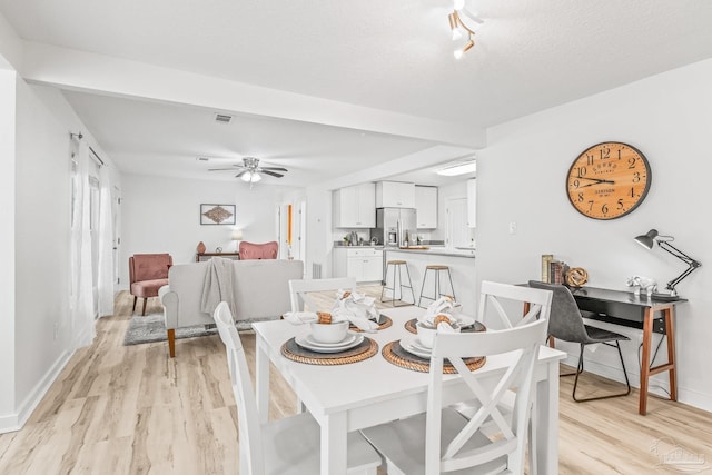 dining area with a textured ceiling, light wood-type flooring, and ceiling fan