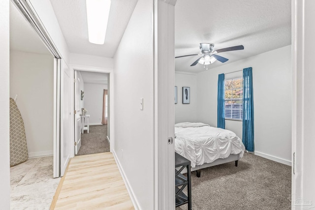 bedroom featuring ceiling fan, light wood-type flooring, and a textured ceiling