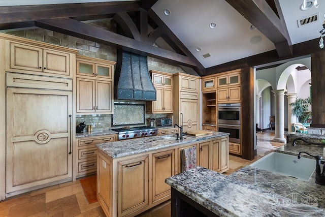 3063 Bay St, Gulf Breeze, FL 32563 - kitchen with ornate columns, stainless steel double oven, a sink, custom range hood, and arched walkways
