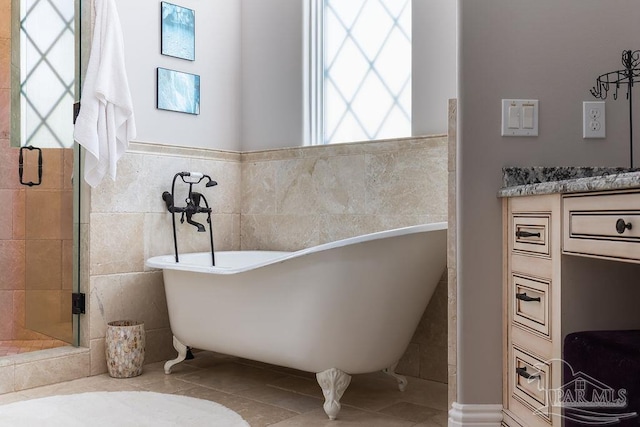 3063 Bay St, Gulf Breeze, FL 32563 - full bathroom with tile patterned floors, tile walls, a freestanding tub, a shower stall, and wainscoting