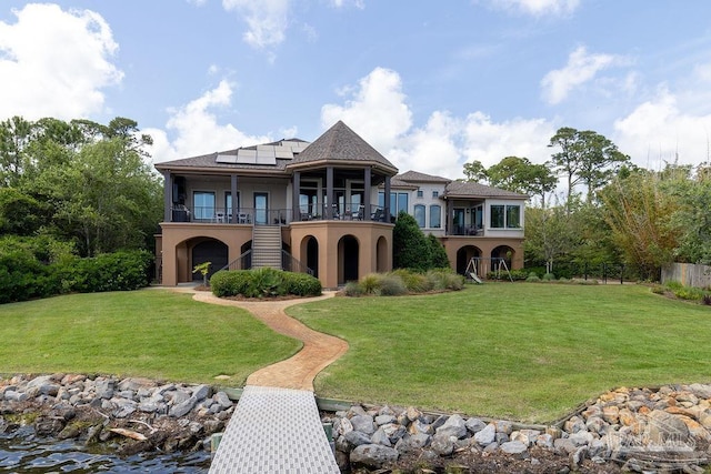 3063 Bay St, Gulf Breeze, FL 32563 - rear view of property with solar panels, a balcony, stucco siding, a yard, and stairs