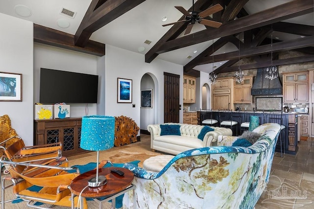 3063 Bay St, Gulf Breeze, FL 32563 - living area featuring arched walkways, beam ceiling, stone tile floors, a ceiling fan, and high vaulted ceiling