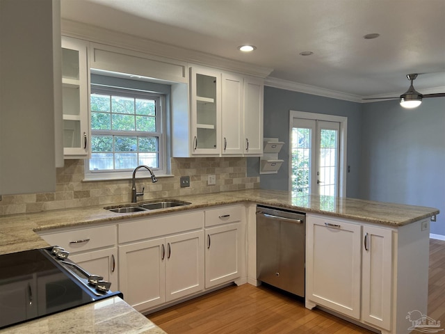 kitchen with a peninsula, a sink, white cabinets, stainless steel dishwasher, and light wood-type flooring