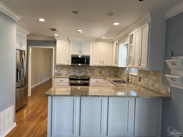 kitchen featuring stainless steel appliances, a peninsula, a sink, visible vents, and white cabinetry