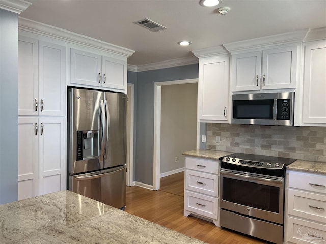 kitchen with appliances with stainless steel finishes, backsplash, visible vents, and crown molding