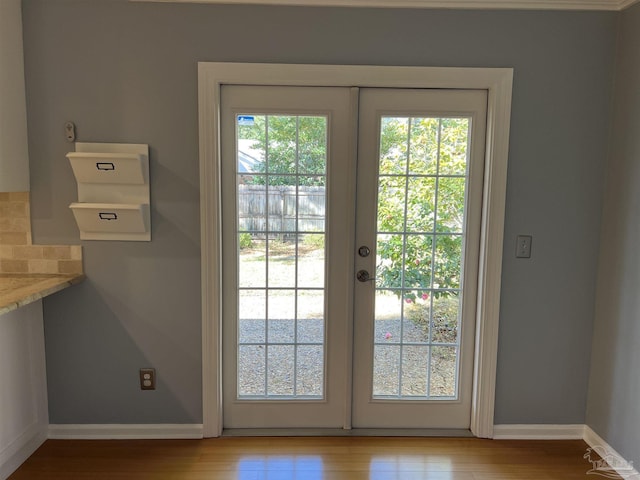 doorway with a healthy amount of sunlight, light wood-style floors, baseboards, and french doors