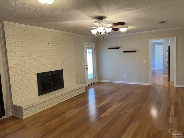 unfurnished living room with a fireplace, crown molding, visible vents, and wood finished floors