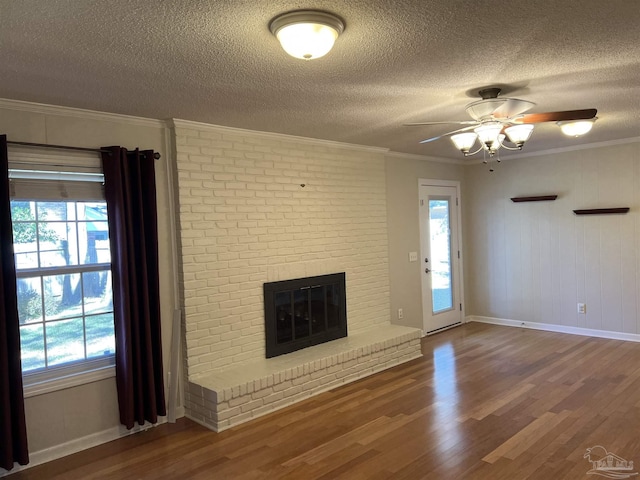 unfurnished living room featuring a fireplace, ornamental molding, a wealth of natural light, and wood finished floors