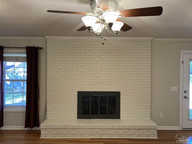 unfurnished living room with a textured ceiling, ornamental molding, a brick fireplace, and wood finished floors