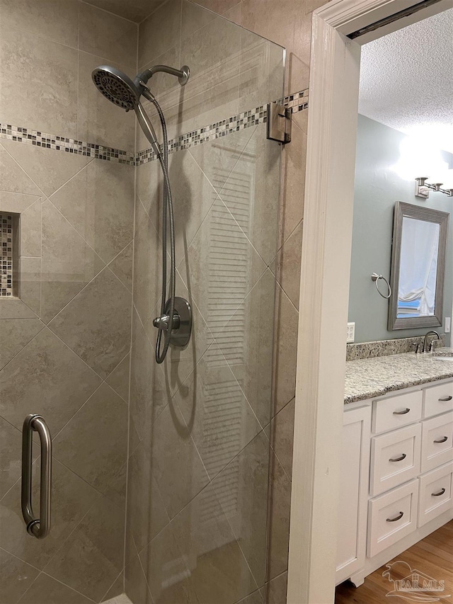 bathroom with a shower stall, vanity, and wood finished floors