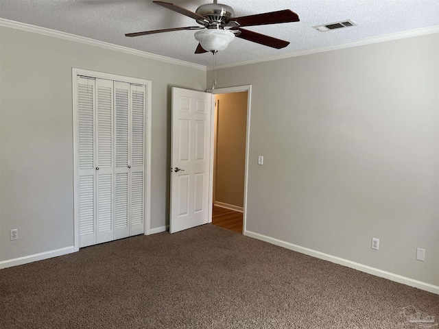 unfurnished bedroom featuring a closet, ornamental molding, carpet flooring, a textured ceiling, and baseboards