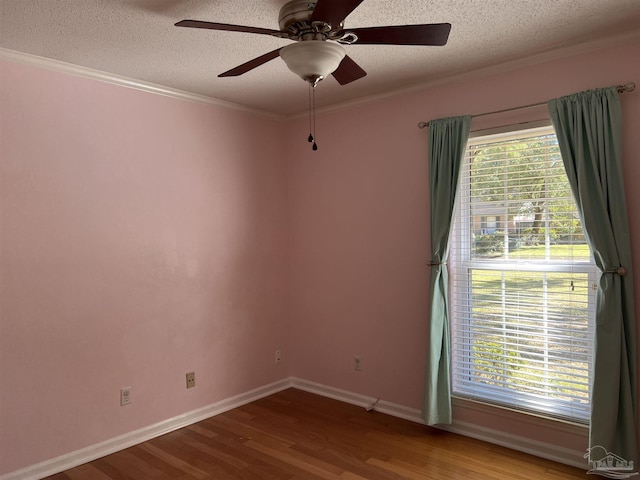 spare room featuring ornamental molding, a textured ceiling, baseboards, and wood finished floors