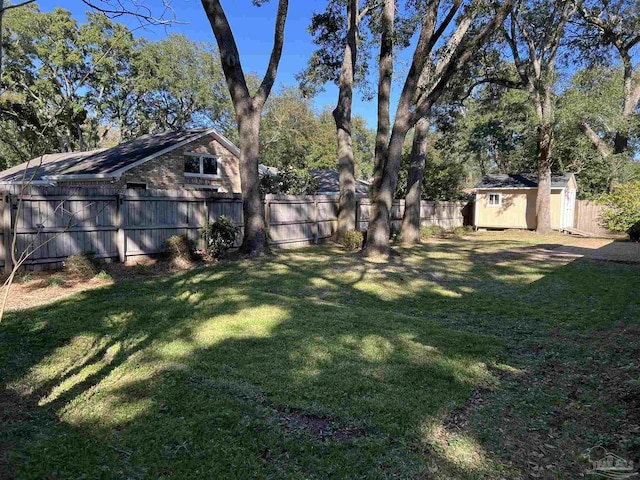 view of yard featuring a storage shed, a fenced backyard, and an outbuilding