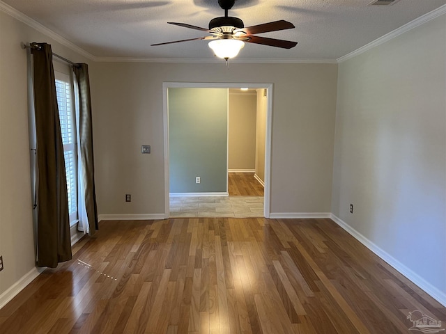 spare room featuring baseboards, a textured ceiling, ornamental molding, and wood finished floors