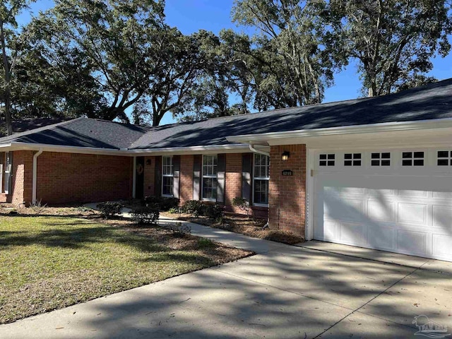 ranch-style home with a front yard, concrete driveway, brick siding, and an attached garage